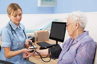 Female nurse doing a blood pressure check up on an old woman
