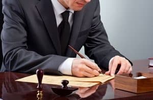 A man in a black suit writing his will